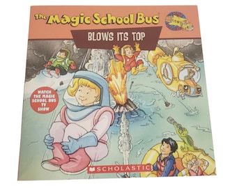 以下が含まれることがあります： 「マジック・スクールバス BLOWS ITS TOP」の表紙には、噴火する火山の漫画イラストが描かれています。宇宙服を着たキャラクターや黄色い潜水艦も描かれています。「Watch The Magic School Bus TV Show」というテキストも含まれています。