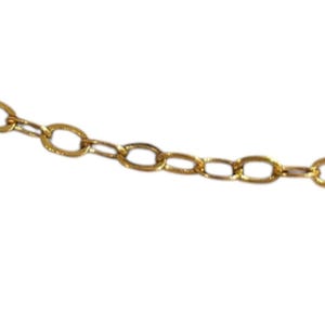 May include: Close-up of a gold necklace clasp and chain. The necklace has a delicate rope chain design that connects to an oval-link extender chain. A small heart-shaped charm hangs near the clasp.