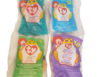 May include: Four Ty plush toys sealed in individual clear plastic McDonald's bags. Each bag features a Ronald McDonald graphic, a red ty heart logo, and a number. The bags are teal, blue, green, and purple, containing toys named Pinchers, Peanut, Twigs, and Stretchy the Ostrich.
