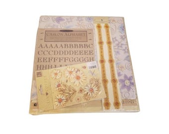 May include: A craft supply set featuring a 12x12 inch paper pad with floral patterns, a sheet of Caslon Alphabet stickers, and a package of die-cut daisy embellishments. The items are packaged together in clear plastic, displaying various letters.