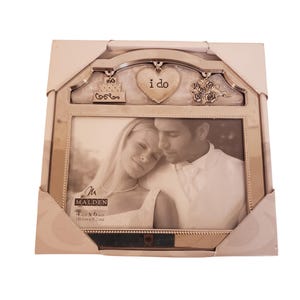 Puede incluir: Marco de fotos de boda de metal plateado con una foto de una pareja. El marco tiene elementos decorativos como un pastel, un corazón con el texto "i do" y rosas. Medidas: 10,1 cm x 15,2 cm.