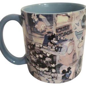 May include: A light blue ceramic mug featuring a collage of vintage Mickey Mouse imagery. The mug has a light blue interior and handle. The collage includes images of Mickey Mouse and text that reads "House Brigade".