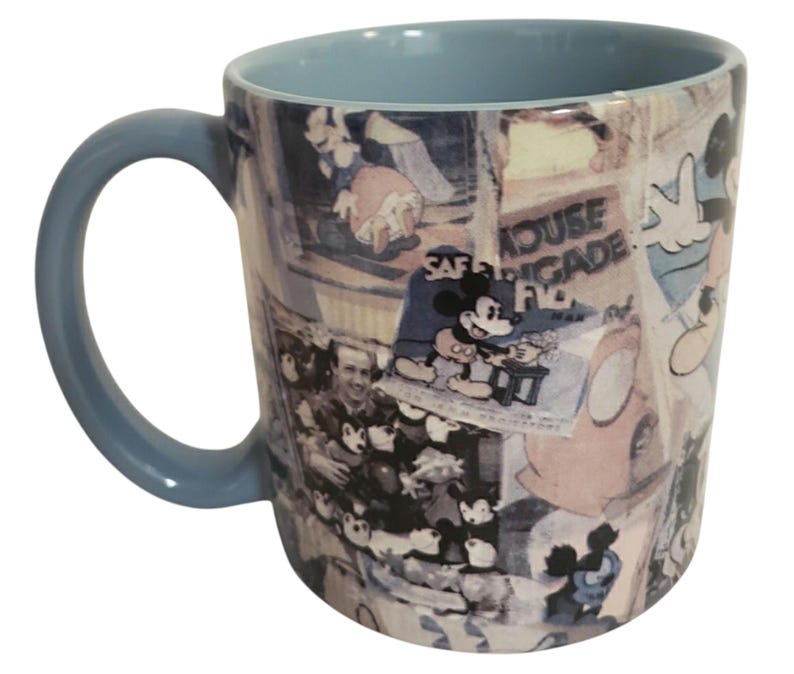 May include: A light blue ceramic mug featuring a collage of vintage Mickey Mouse imagery. The mug has a light blue interior and handle. The collage includes images of Mickey Mouse and text that reads "House Brigade".