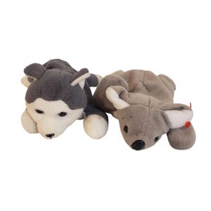 May include: Two plush animal toys. One is a gray and white husky dog with black eyes and a black nose. The other is a gray koala bear with white inner ears and a black nose. Both toys are lying down.