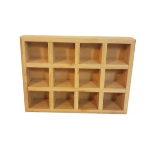 May include: A light-colored wooden organizer with twelve square compartments arranged in three rows of four. The organizer is made of natural wood and has a simple, boxy design. It is suitable for storing small items.
