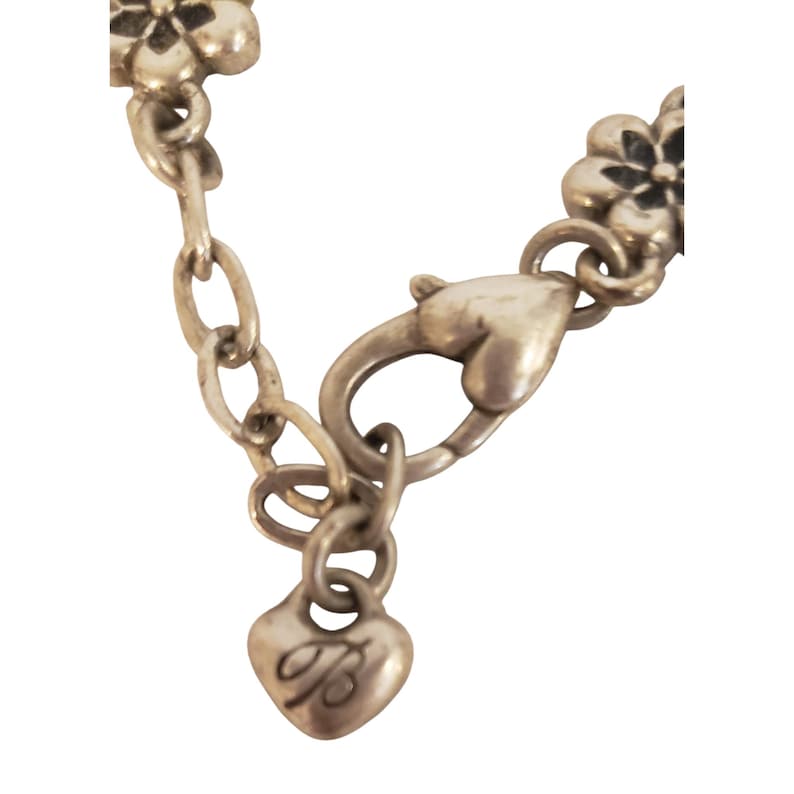 Pode incluir: Close-up de um fecho e corrente de colar prateados. O fecho tem formato de cora&ccedil;&atilde;o e a corrente apresenta pequenos detalhes florais. Um pequeno pingente de cora&ccedil;&atilde;o com a letra "B" est&aacute; preso &agrave; corrente.