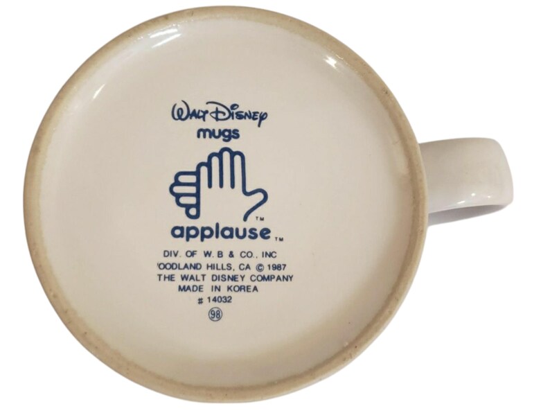 K&ouml;nnte beinhalten: Ein Set aus drei Keramikbechern mit einer gesprenkelten, cremefarbenen Glasur. Jeder Becher hat ein anderes handgemaltes Design: ein blaues und gr&uuml;nes Blatt, eine gelbe Blume und eine rote Beere. Die Becher haben ein schlichtes, modernes Design.