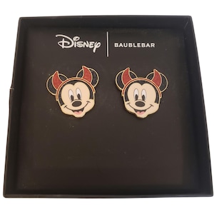May include: Two Mickey Mouse face pins in a black box. The pins feature a gold outline, a red and black hat, and a smiling face. The box has the Disney and Baublebar logos.