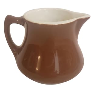 Może przedstawiać: Mały, brązowy ceramiczny dzbanuszek do śmietanki z białym wnętrzem. Dzbanuszek ma zaokrąglony korpus, uchwyt i dzióbek do nalewania. Błyszczące wykończenie odbija światło, podkreślając gładką powierzchnię.