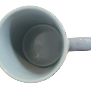 May include: A light blue ceramic mug with a matching handle. The interior of the mug is a darker shade of blue. The mug is empty and viewed from above.