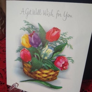 May include: A get well card with the message "A Get Well Wish for You" printed on the front. The card features a basket of colorful tulips.