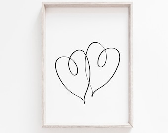 May include: A black and white line drawing of two intertwined hearts in a simple, minimalist style. The drawing is framed in a light wood frame and displayed on a white wall.