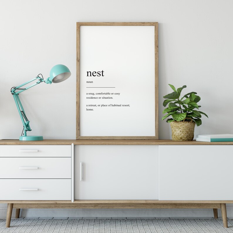 Peut inclure: Une affiche encadr&eacute;e avec le mot "nest" d&eacute;fini comme une r&eacute;sidence ou une situation confortable, douillette ou accueillante, et un lieu de retraite ou de s&eacute;jour habituel, un foyer.
