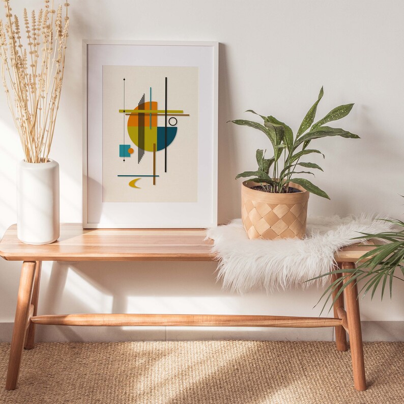 Puede incluir: Un banco de madera con una manta de piel sint&eacute;tica blanca y una planta en maceta. Una impresi&oacute;n enmarcada con un dise&ntilde;o abstracto geom&eacute;trico en amarillo, naranja y azul cuelga de la pared sobre el banco.