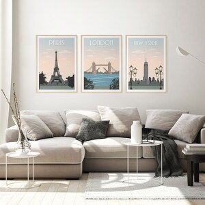 Puede incluir: Tres impresiones enmarcadas de paisajes urbanos con los nombres "Par&iacute;s", "Londres" y "Nueva York" sobre cada imagen. La impresi&oacute;n de Par&iacute;s presenta la Torre Eiffel, la impresi&oacute;n de Londres presenta el Tower Bridge y la impresi&oacute;n de Nueva York presenta el Empire State Building.