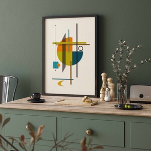 Puede incluir: Una impresi&oacute;n geom&eacute;trica abstracta enmarcada con un esquema de color amarillo, naranja, azul y verde. La impresi&oacute;n est&aacute; colgada en una pared verde sobre una encimera de madera.