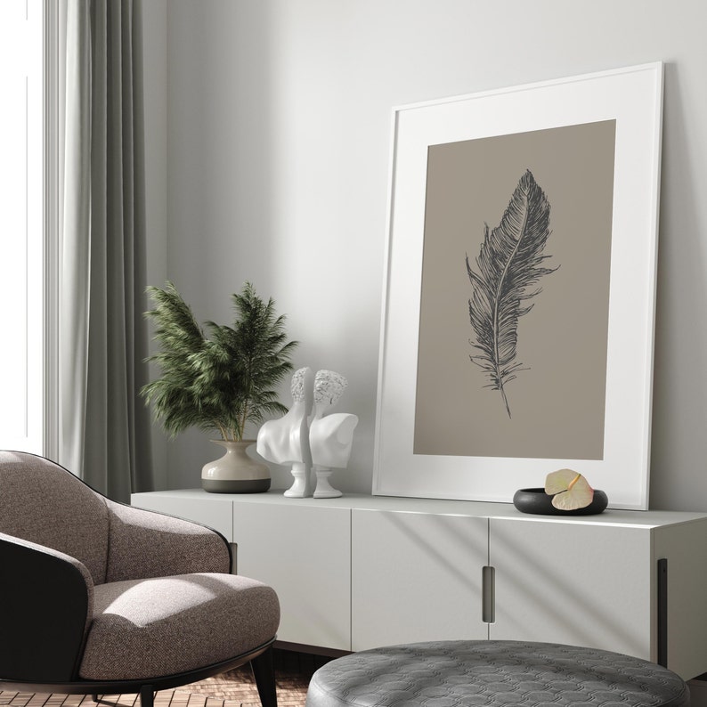 May include: A white cabinet with two doors and a white framed print of a black feather on a beige background. There are two white statues and a potted plant on top of the cabinet.