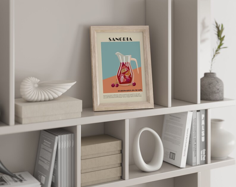 May include: A framed print featuring a Sangria illustration with a pitcher filled with fruit and the text "Sangria" at the top. The print is displayed on a white shelf with decorative items, including a seashell, boxes, and books. The color palette includes beige, red, and teal.