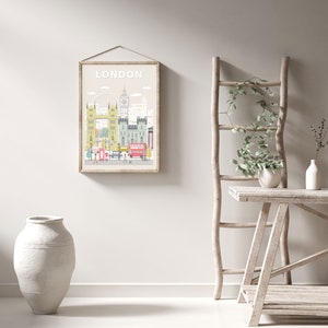 May include: A framed illustration of the London skyline with the word "LONDON" in white text at the top. The illustration features iconic landmarks like Big Ben, the London Eye, and Tower Bridge. The illustration is in a light beige frame and is hanging on a white wall.