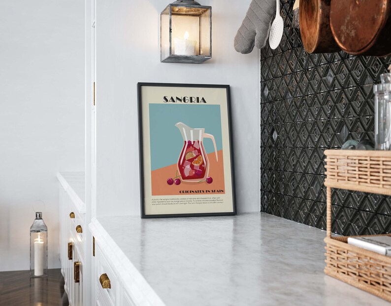 May include: A framed art print featuring a Sangria illustration. The artwork depicts a pitcher filled with red sangria, fruit slices, and cherries, set against a teal and peach background. The print is displayed in a kitchen setting.