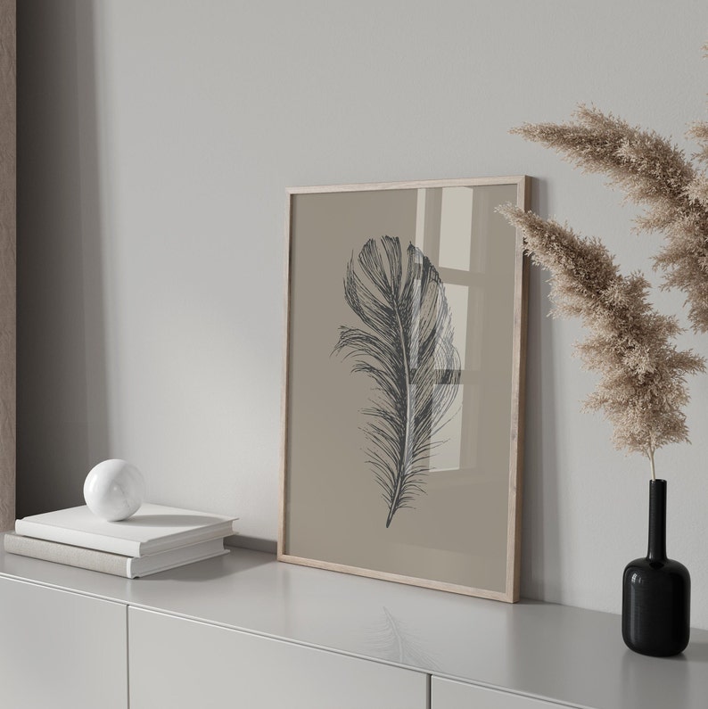 May include: A framed print of a black and white illustration of a single feather on a beige background.