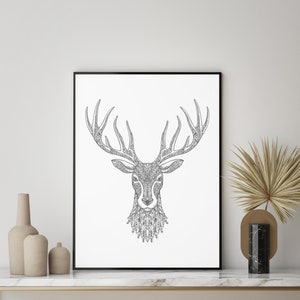 May include: A black and white line art print of a deer's head with intricate patterns in the antlers and fur. The print is framed in a black frame and is hanging on a white wall.