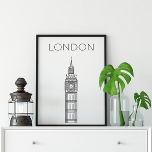 May include: Black and white line art print of Big Ben with the word "LONDON" above it. The print is framed in a black frame and is hanging on a white wall.