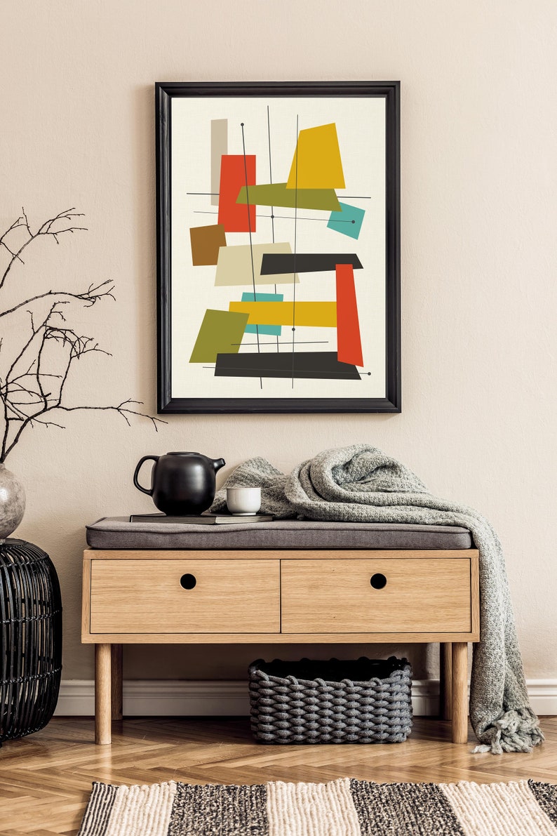 May include: A framed abstract art print with geometric shapes in red, yellow, green, blue, and black on a white background. The print is hanging on a beige wall above a wooden bench with two drawers.