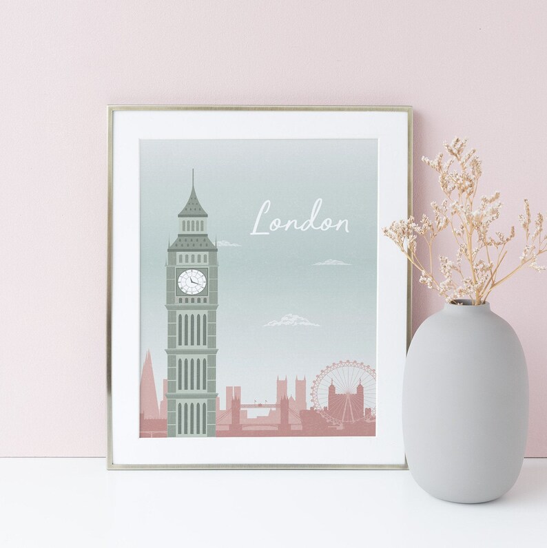 May include: A framed print featuring a London skyline illustration. The artwork showcases Big Ben, the London Eye, and other landmarks in muted tones of green and pink. The word "London" is written in a script font.