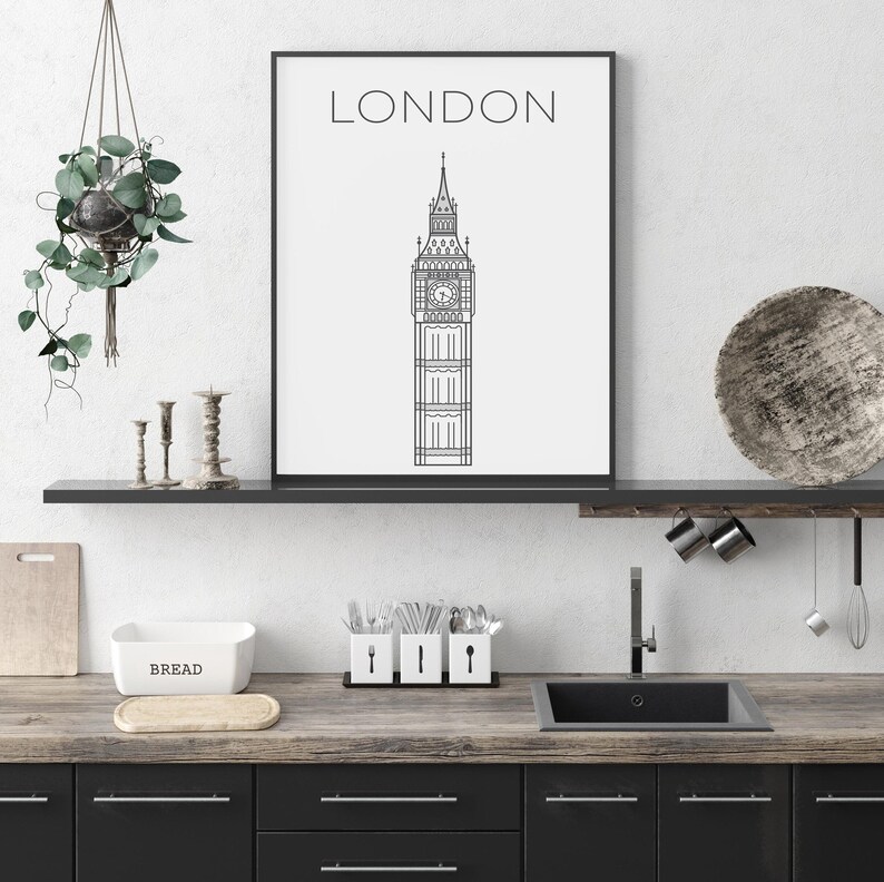 May include: Black and white line art print of Big Ben with the word "LONDON" at the top. The print is framed and hanging on a white wall above a kitchen counter.