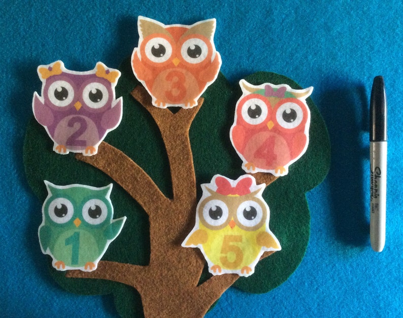 May include: Five felt owls with numbers 1 through 5 on a brown tree trunk with green leaves. The owls are different colors: purple, orange, red, green, and yellow.