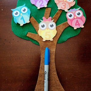 May include: A felt tree with five owls on it. Each owl has a number on it, from 1 to 5. The owls are different colors, including pink, blue, purple, orange, and yellow.