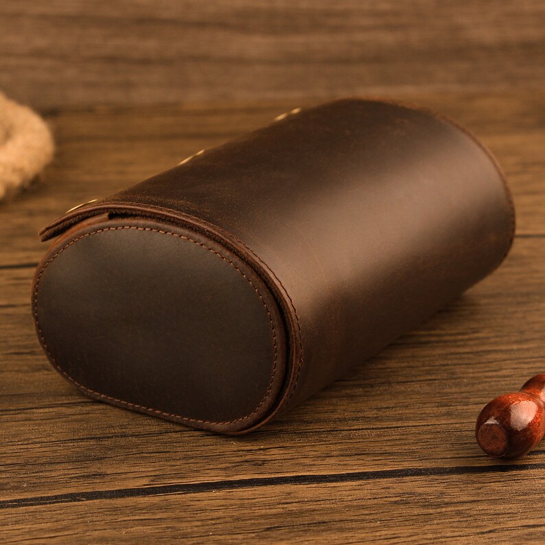 Peut inclure: Un &eacute;tui cylindrique en cuir marron avec une couture sur le bord. L'&eacute;tui est fait d'un cuir souple et doux et a une finition lisse et polie.