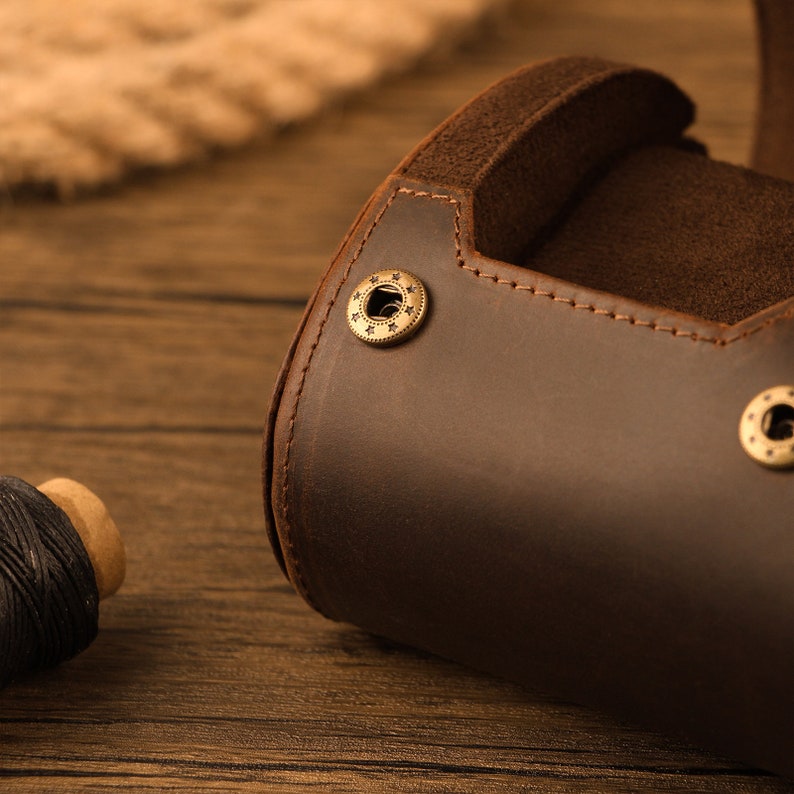 Peut inclure: Gros plan sur un &eacute;tui pour appareil photo en cuir marron avec un bouton en laiton. L'&eacute;tui est fait de cuir de haute qualit&eacute; et poss&egrave;de une doublure en daim douce.