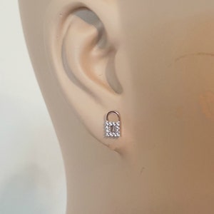 May include: A pair of silver padlock earrings with clear cubic zirconia stones.