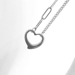 May include: A silver necklace with a heart-shaped pendant and a chain with a link design.