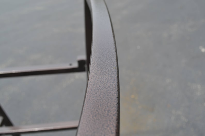 May include: Close-up of a curved metal railing with a textured, dark brown finish.
