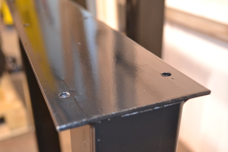 May include: Black metal table leg with two screw holes on the top surface.