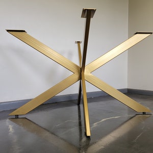 May include: Gold metal table base with a starburst design. The base has five points and is made of a single piece of metal.
