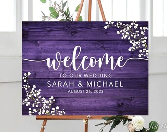 Puede incluir: Señal de bienvenida de madera púrpura con detalles florales blancos y el texto "Bienvenido a nuestra boda Sarah & Michael 26 de agosto de 2023".