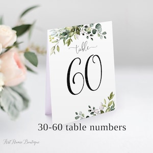 May include: White table number card with green watercolor foliage and the text "table 60".