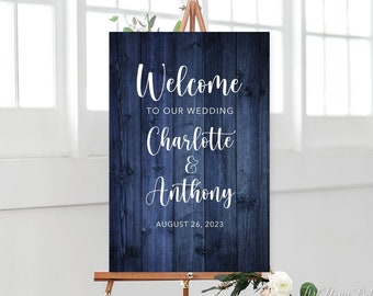 May include: Welcome sign for a wedding with a rustic woodgrain background in a dark blue colour. The sign says "Welcome to our wedding Charlotte & Anthony August 26, 2023".