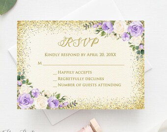 May include: An RSVP card with a gold glitter border and floral accents in purple and white. The card includes the text "RSVP" and prompts for a response by a specific date. The design features a soft, elegant aesthetic, suitable for weddings or special events.