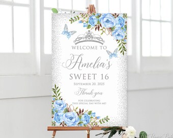 Könnte beinhalten: Ein Willkommens-Schild für eine Sweet-16-Party mit silbernem Glitzer-Hintergrund, blauen Blumen, Schmetterlingen und einer silbernen Krone. Der Text lautet "Willkommen bei Amelia's Sweet 16 September 20, 2025 Danke, dass du diesen besonderen Tag mit mir feierst!"