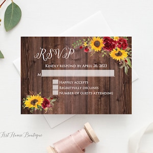 May include: RSVP card with a rustic wood background, adorned with watercolor sunflowers and burgundy roses. The card includes fields for the recipient's name, acceptance, and guest count, with a request to respond by April 20, 2023.