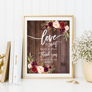 May include: A printable sign with a rustic wood background and burgundy and blush floral accents. The text reads "love is sweet enjoy a treat thank you for making our day complete".