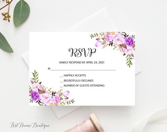 May include: A white RSVP card featuring floral decorations in purple and lavender hues. The card is inscribed with "RSVP" and requests a response by April 24, 2021. It includes sections for acceptance, regrets, and the number of guests attending.