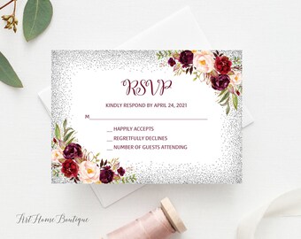 May include: A silver glitter RSVP card with a floral design featuring burgundy and pink flowers. The text on the card reads "RSVP" and "Kindly respond by April 24, 2021".