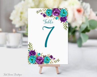 May include: White table number card with teal and purple floral design. The card reads "Table 7".