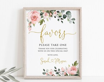 May include: A white sign with a gold floral border and the text "favors" in gold script. The sign also includes the text "Please take one" and "Thank you for celebrating with us on this special day!" in black text. The sign is signed "Sarah Mason" with a heart symbol between the names.